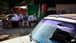 Para pendukung presiden Mesir yang terguling, Mohammed Morsi, melancarkan aksi duduk di dekat mobil yang rusak akibat bentrokan dengan polisi di daerah kampus Universitas Kairo, Giza, Mesir (23/7).