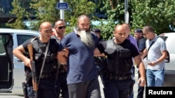 FILE - Kosovo police escort a man suspected of having fought with Islamist insurgents in Syria and Iraq, in Pristina, Aug. 12, 2014. Kosovo has taken a proactive approach to reintegrating citizens who joined the IS.