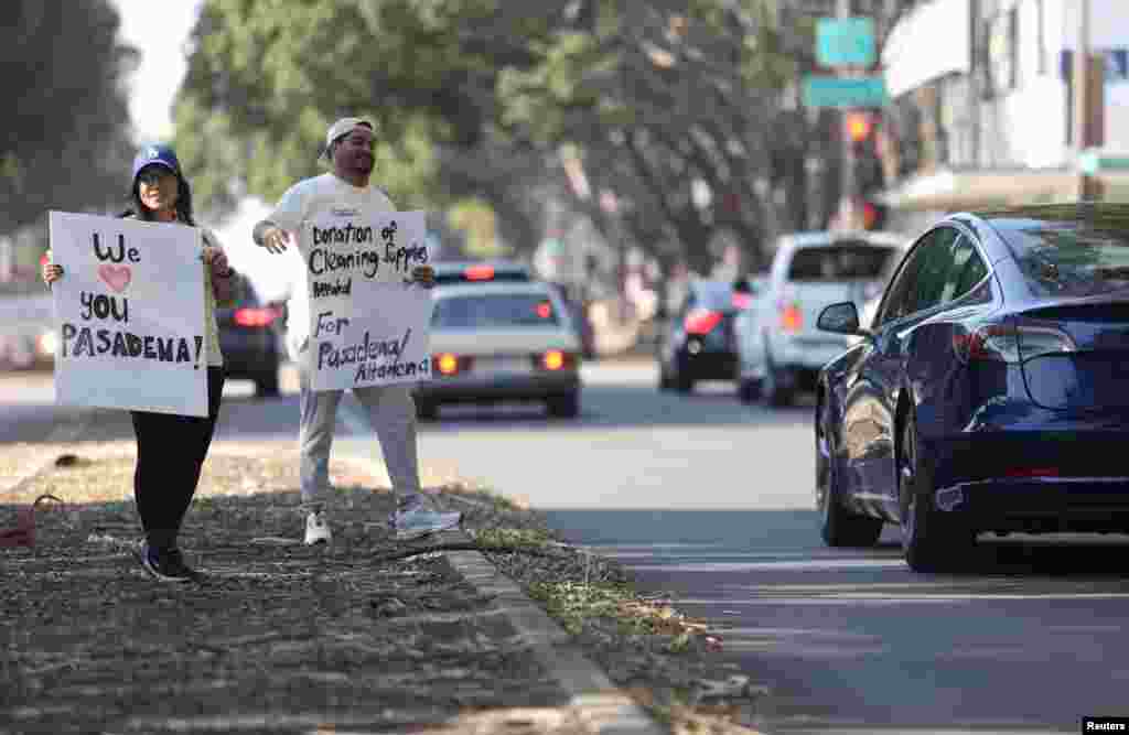 People hold signs asking for donations for people affected by the Eaton fire in Pasadena, California, Jan. 11, 2025.