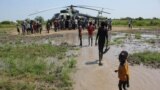 Civilians displaced by flooding gather at a military helicopter to receive relief support in Gumuruk, Boma state, in the Greater Upper Nile region of South Sudan, Nov. 1, 2019.