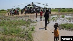 Civilians displaced by flooding gather at a military helicopter to receive relief support in Gumuruk, Boma state, in the Greater Upper Nile region of South Sudan, Nov. 1, 2019.