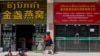 FILE - A woman walks in front of Chinese stores in Laos' capital, Vientiane, on Oct. 8, 2024.