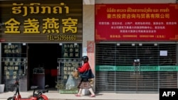 FILE - A woman walks in front of Chinese stores in Laos' capital, Vientiane, on Oct. 8, 2024.