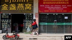 This photo taken on Oct. 8, 2024, shows a woman walking in front Chinese stores in Laos' capital, Vientiane.