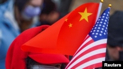 Seseorang memegang bendera AS dan China di kawasan Chinatown di Manhattan borough New York City, New York, AS, 12 Februari 2021. (Foto: REUTERS/Carlo Allegri)