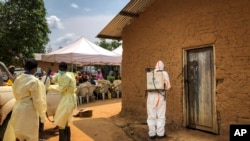 Seorang pekerja dari Organisasi Kesehatan Dunia (WHO) menyemprotkan disinfektan di depan sebuah rumah di mana dua kasus infeksi Ebola di temukan di Desa Mabalako, di timur Kongo, 17 Juni 2019.