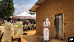 Petugas medis dari Organisasi Kesehatan Dunia (WHO) mendekontaminasi pintu sebuah rumah di desa Mabalako, di Kongo timur, di mana dua kasus Ebola ditemukan, Senin, 17 Juni 2019. (Foto: dok).