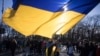 FILE - A woman waves a giant Ukrainian flag during a protest to mark two years since Russia's full-scale invasion on Ukraine, at the Brandenburg Gate, in Berlin, Saturday, Feb. 24, 2024. 