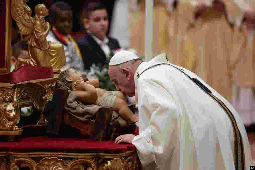Pope Francis kisses a statue of Baby Jesus as he celebrates Christmas Eve Mass in St. Peter&#39;s Basilica at the Vatican, Dec. 24, 2019.