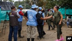 FILE - A United Nations observer shakes hands with a rebel of the Revolutionary Armed Forces of Colombia (FARC) before a meeting in La Carmelita, Colombia, March 1, 2017. A FARC splinter group on Wednesday released a U.N. contractor it had taken hostage in May.