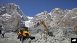 Pakistani soldiers use heavy machinery to dig through the snow at the site of an avalanche and landslide that struck a Pakistani army battalion headquarters, at the Siachen Glacier in Kashmir, April 18, 2012.