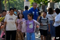 FILE - People pick up their children after school in Beijing, Friday, Sept. 13, 2024. (AP Photo/Andy Wong)