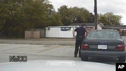 In this April 4, 2015, frame from dashboard video provided by the North Charleston Police Department, Patrolman Michael Thomas Slager stands by Walter Lamer Scott's car during a traffic stop in North Charleston, S.C. 