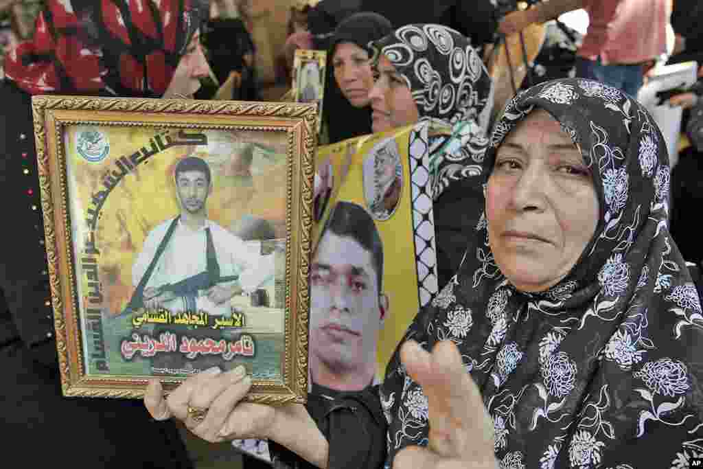 A Palestinian woman flashes the "V" for victory sign as she holds a picture of a relative held in an Israeli prison during a gathering at the Red Cross' offices in Gaza City to celebrate the upcoming release of Palestinian inmates from Israeli jails, Oct