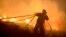 A firefighter gathers hoses while fighting a forest fire near the Basque town of Berango, near Bilbao, northern Spain, Dec. 28, 2015. 