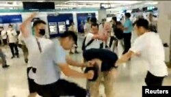 Men in white T-shirts and face masks attack anti-extradition bill demonstrators and reporters at a train station in Hong Kong, China, July 21, 2019, in this still image obtained from a social media live video.