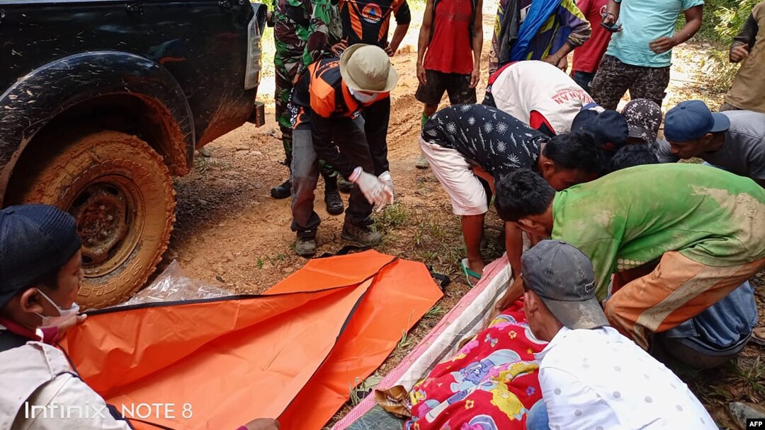 Foto handout yang diambil pada 11 Mei 2021 dan dirilis oleh Badan Nasional Penanggulangan Bencana Indonesia (BNPB) ini menunjukkan tim penyelamat mengambil jenazah setelah tanah longsor di tambang emas di Solok selatan, Sumatera Barat di mana setidaknya t
