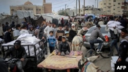 Seorang pria Palestina mengantar bantuan kemanusiaan dengan motor di tengah sejumlah warga Palestina yang juga berupaya mendapatkan bantuan di luar kantor UNRWA di Rafah, selatan Jalur Gaza, pada 3 Maret 2024. (Foto: AFP)