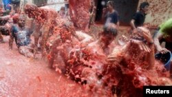 Para pengunjung basah oleh tomat-tomat yang saling dilemparkan dalam festival tahunan Tomatina di Kota Bunol, dekat Valencia, Spanyol, 30 Agustus 2018.