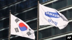 The company flag of Samsung Electronics (right) flutters next to the South Korean national flag in Seoul, South Korea, Jan. 16, 2017.