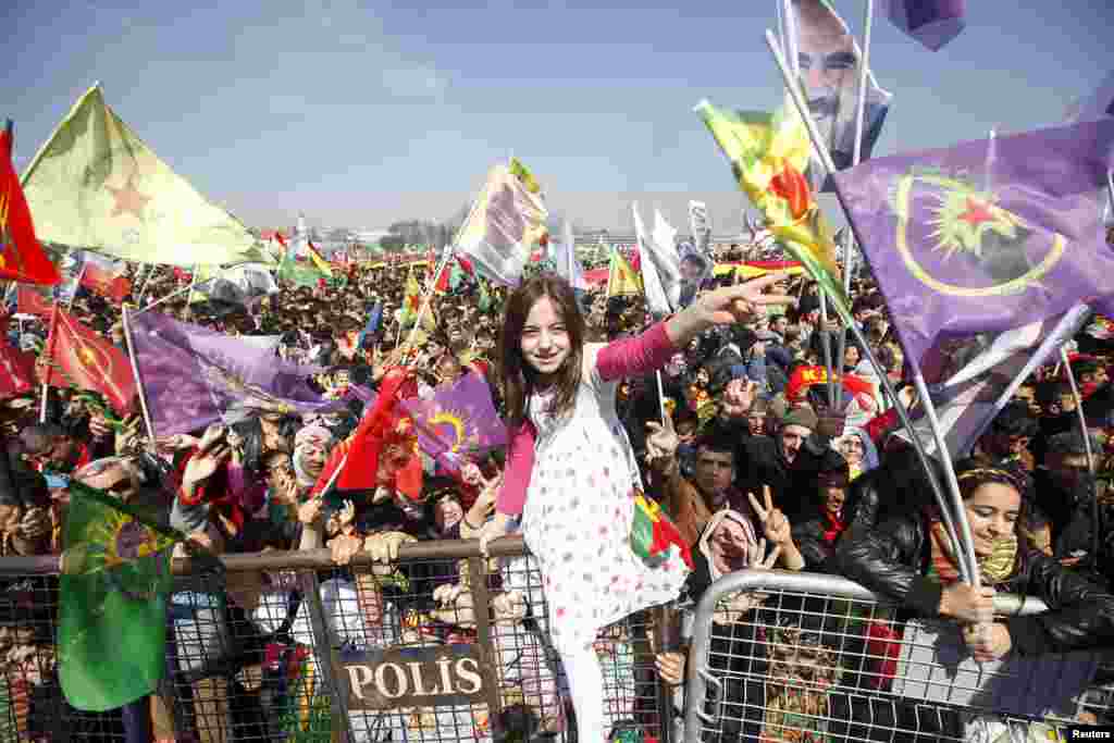 A girl gestures while others wave Kurdish flags during a gathering celebrating Newroz, which marks the arrival of spring and the new year, in Istanbul, Turkey.