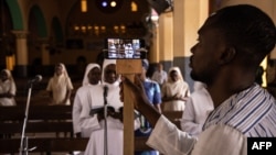 ARCHIVES - Un homme utilise un téléphone pour diffuser en direct sur les réseaux sociaux la messe traditionnelle du dimanche de Pâques à la cathédrale de l'Immaculée Conception à Ouagadougou, au Burkina Faso, le 12 avril 2020.