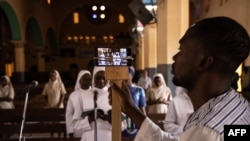FILE - A man uses a phone to broadcast the traditional Easter Sunday mass live on social media at the Cathedral of the Immaculate Conception in Ouagadougou, Burkina Faso, April 12, 2020. 