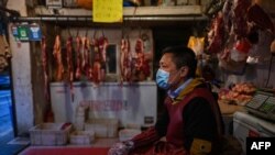 A vendor wearing a face mask waits for customers at a meat stall in Wuhan in China's central Hubei province on April 18, 2020.