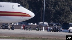 Warga AS yang dievakuasi dari Wuhan, China masuk ke dalam bus, China, setibanya di Pangkalan Udara di Riverside, California, 39 Januari 2020. 