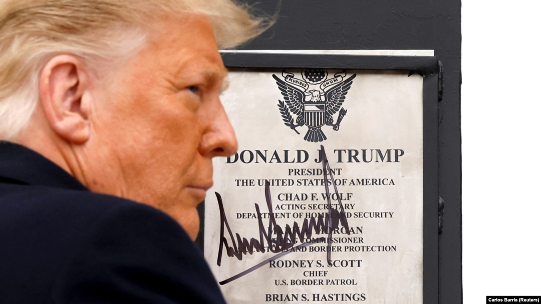 Presiden Donald Trump menandatangani plakat yang dipasang di tembok perbatasan AS-Meksiko dalam lawatan ke Alamo, Texas, Selasa, 12 Januari 2021. (Foto: Reuters)