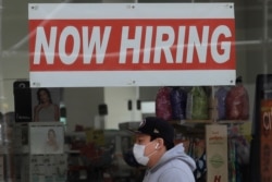 A man wears a mask during the coronavirus outbreak while walking under a Now Hiring sign at a CVS Pharmacy in San Francisco, May 7, 2020.
