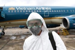 In this file photo taken on March 3, 2020 a worker wearing a protective suit prepares to disinfect a Vietnam Airlines plane amid concerns of the spread of the coronavirus at Noi Bai International Airport in Hanoi.