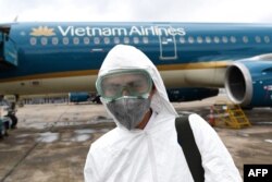 In this file photo taken on March 3, 2020 a worker wearing a protective suit prepares to disinfect a Vietnam Airlines plane amid concerns of the spread of the coronavirus at Noi Bai International Airport in Hanoi.