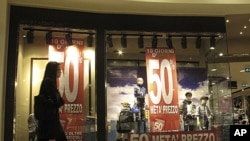 A woman walks past the window of a clothes store announcing 50 percent discounts in downtown Milan, Italy, November 7, 2011.