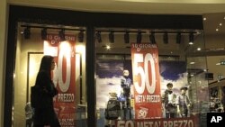 A woman walks past the window of a clothes store announcing 50 percent discounts in downtown Milan, Italy, November 7, 2011.