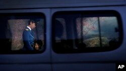 A North Korean traffic police woman is framed by a window of a passing vehicle as she walks past commuters waiting at a bus stop at the end of a workday on Monday, Oct. 17, 2016, in Pyongyang, North Korea. 