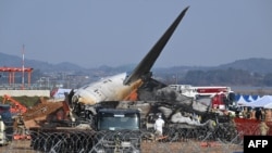 Petugas pemadam kebakaran dan petugas penyelamat bekerja di dekat reruntuhan pesawat Boeing 737-800 Jeju Air setelah jatuh dan terbakar di Bandara Internasional Muan di Provinsi Jeolla Selatan. (Foto: AFP)