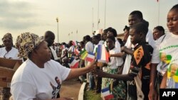 La mère du président gabonais Ali Bongo Ondimba, à gauche, remet des drapelets à quelques personnes à l’aéroport de Franceville, Gabon, 23 février 2010.