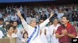 ARCHIVO - En esta fotografía de archivo del 25 de abril de 1990, la entonces nueva presidenta de Nicaragua, Violeta Barrios de Chamorro, recibe la banda del presidente saliente, Daniel Ortega, en Managua, Nicaragua.