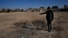 FILE - A man shows a crater where a surface-to-surface missile loaded with sarin struck, during a 2013 chemical weapons attack that was blamed on then President Bashar al-Assad's forces, on the outskirts of Damascus, Syria, Dec. 25, 2024.