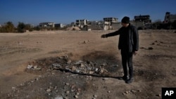 FILE - A man shows a crater where a surface-to-surface missile loaded with sarin struck, during a 2013 chemical weapons attack that was blamed on then President Bashar al-Assad's forces, on the outskirts of Damascus, Syria, Dec. 25, 2024.