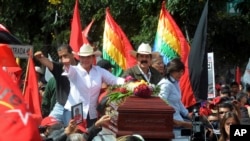 Kandida a la prezidans Xiomara Castro (agoch) ak mari li, Manuel Zelaya, sou tèt yon machin kap transpòte sèkèy yon patizan ki te mouri samdi premye desanm nan anba men swadizan kriminèl (Tegucigalpa, dimanch premye desanm 2013).