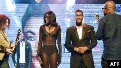 Les mannequins Awa Sanoko (2e à gauche) et Tony Santana (2e à droite) sont sur le point de recevoir un prix lors du 8ème African Model Exhibition Awards à Abidjan, le 15 décembre 2017.