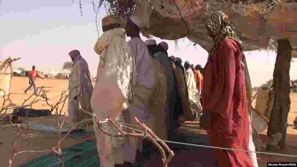 Des hommes prient, le visage balayé par le vent et le sable, dans le camp Assaga de Diffa, au Niger, le 3 mars 2016. (VOA/Nicolas Pinault)