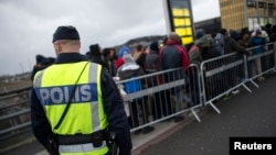 Un policier monte la garde à l’arrivée des migrants à la gare Hyllie près de Malmö, en Suède, 19 novembre 2015.