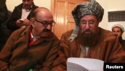 FILE- Maulana Sami ul-Haq (R), one of the Taliban negotiators, and Irfan Siddiqui, a government negotiator, discuss a joint statement before a news conference in Islamabad, Pakistan, Feb. 6, 2014.