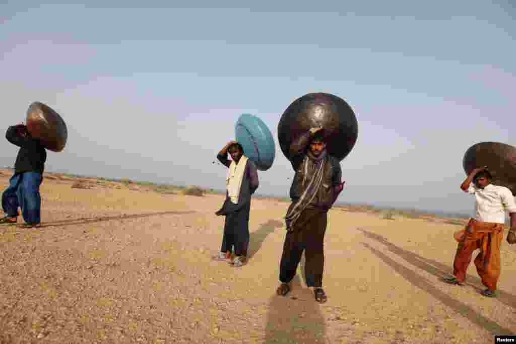 Men carry floating pitchers that they use to catch fish while heading home in Soneri village next to Keenjhar Lake, near Thatta, Pakistan, Feb. 22, 2015.
