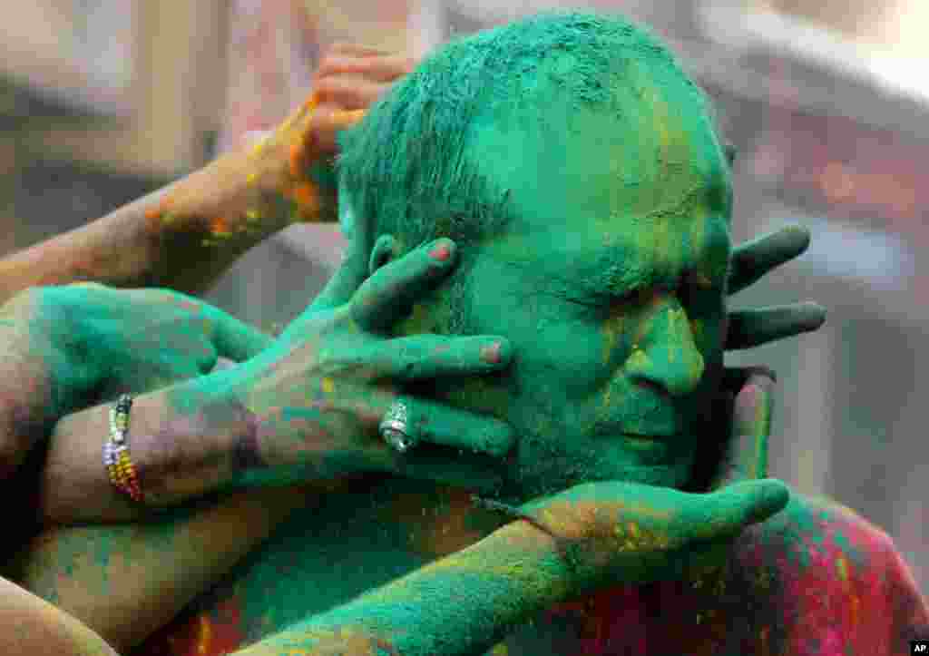 Indians smear colored powder on each other as they celebrate Holi in Jammu.