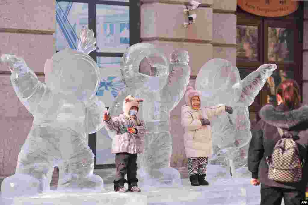 Children play with an ice sculpture of three astronauts in Harbin in China&#39;s northeastern Heilongjiang province.