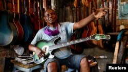 Guitar luthier Misoko Nzalayala Jean-Luther, alias Socklo, 61, gestures while he holds one of his instruments at his workshop in Kinshasa, Democratic Republic of Congo, Oct.18, 2021.